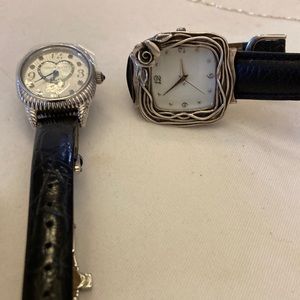 2 designer watches with black leather bands.